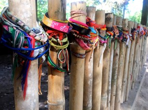 Prayer bracelets around a fenced in mass grave